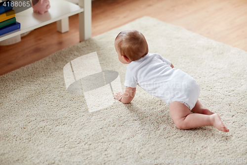 Image of little baby in diaper crawling on floor at home