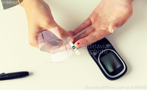 Image of close up of woman making blood test by glucometer