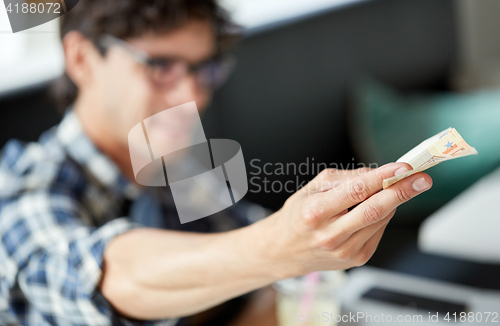 Image of happy man with cash money paying at cafe