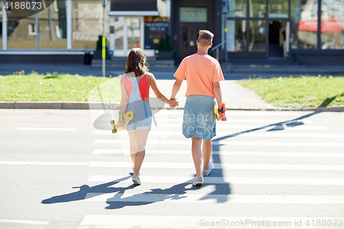 Image of teenage couple with skateboards on city crosswalk