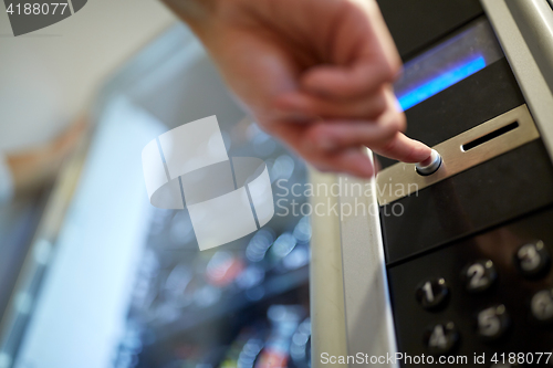 Image of hand pushing button on vending machine