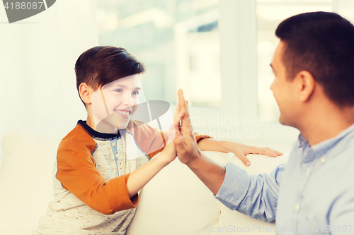 Image of happy father and son doing high five at home