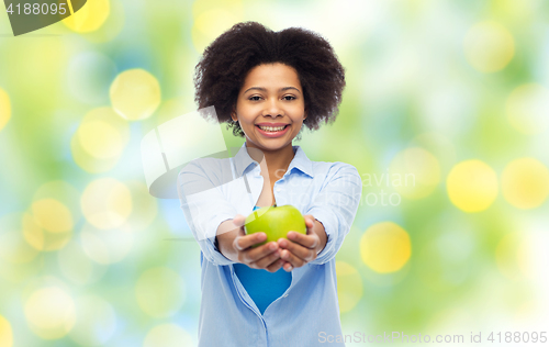 Image of happy african american woman with green apple