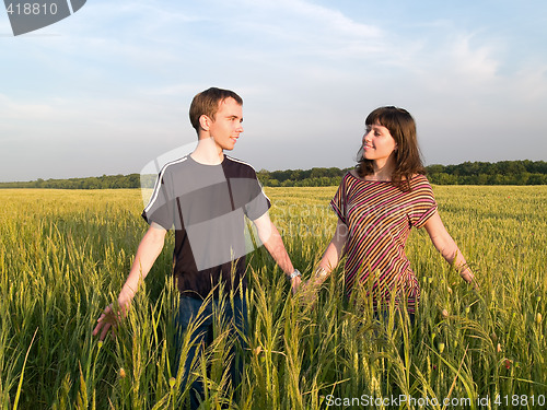 Image of Young Couple Walking Field Holding Hands