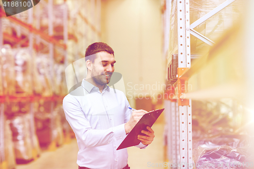 Image of happy businessman with clipboard at warehouse