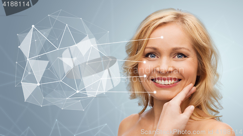 Image of smiling woman with bare shoulders touching face