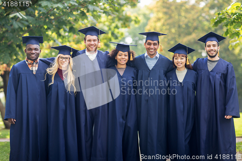 Image of happy students or bachelors in mortar boards