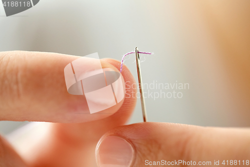 Image of hands of tailor woman threading needle