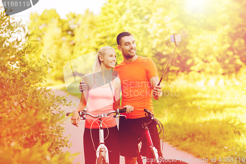 Image of couple with bicycle and smartphone selfie stick