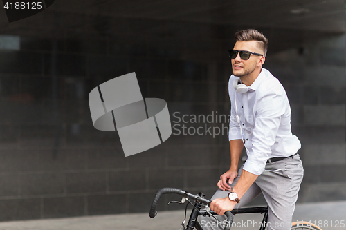 Image of man with bicycle and headphones on city street