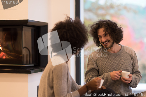 Image of multiethnic couple  in front of fireplace