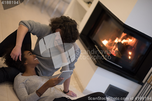 Image of multiethnic couple used tablet computer on the floor