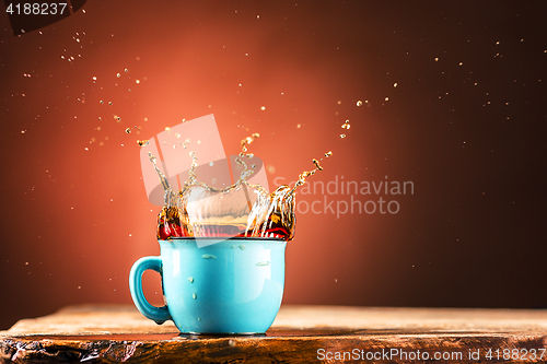 Image of Brown splashes out drink from cup of tea on a brown background