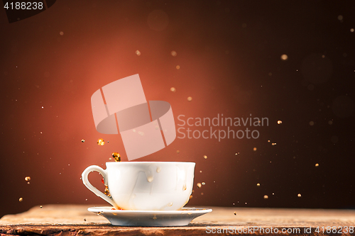 Image of Brown splashes out drink from cup of tea on a brown background