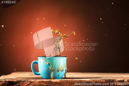 Image of Brown splashes out drink from cup of tea on a brown background