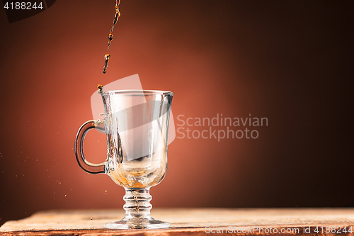 Image of Brown splashes out drink from cup of tea on a brown background