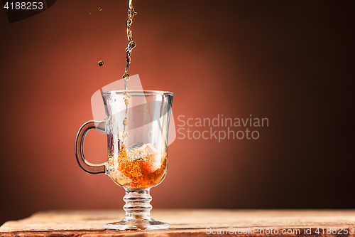 Image of Brown splashes out drink from cup of tea on a brown background