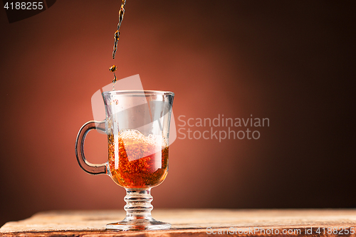 Image of Brown splashes out drink from cup of tea on a brown background