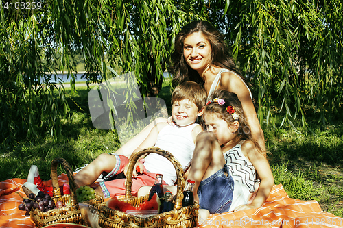 Image of cute happy family on picnic laying on green grass mother and kid