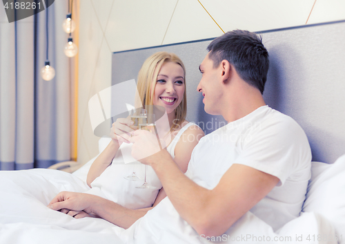 Image of smiling couple with champagne glasses in bed