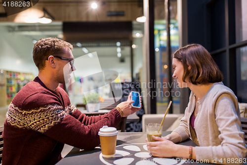 Image of happy couple with smartphone and drinks at cafe
