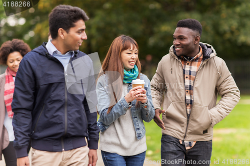 Image of happy friends walking along autumn park