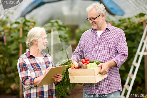 Image of senior couple with box of vegetables on farm