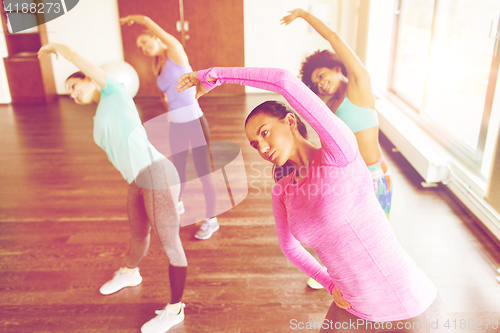 Image of group of women exercising and stretching in gym