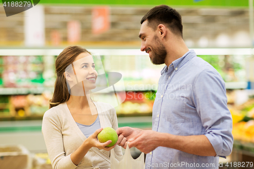 Image of happy couple buying apples at grocery store