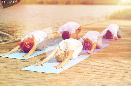 Image of group of people making yoga exercises outdoors