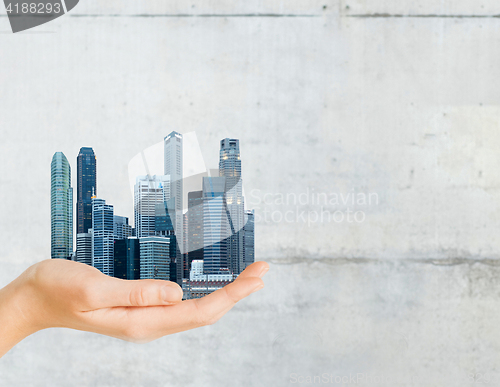 Image of hand holding city over gray concrete background
