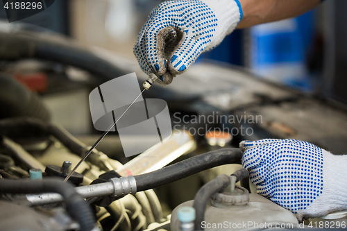 Image of mechanic with dipstick checking motor oil level