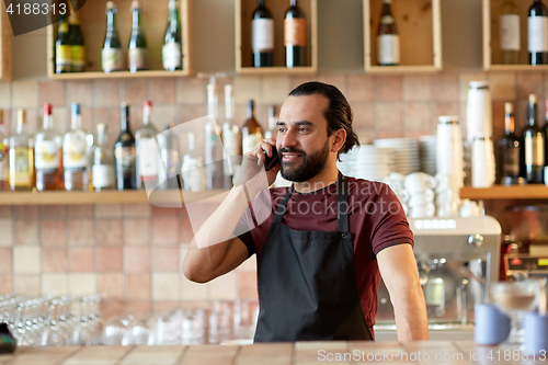 Image of happy man or waiter at bar calling on smartphone