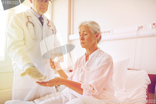 Image of doctor giving medicine to senior woman at hospital