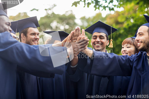 Image of happy students in mortar boards making high five