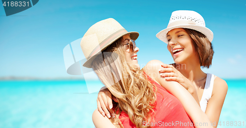 Image of happy young women in hats on summer beach