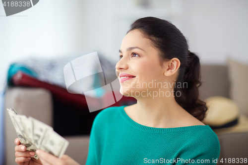 Image of happy woman with money planning her travel at home