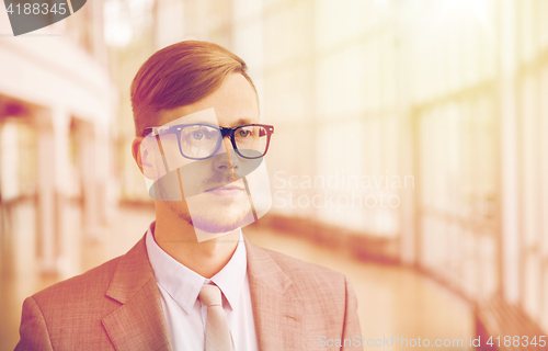 Image of young businessman in suit and glasses at office