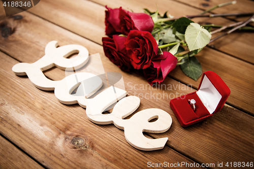 Image of close up of diamond ring, red roses and word love