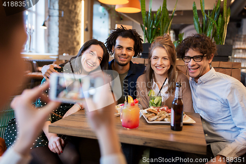 Image of friends with smartphone photographing at cafe