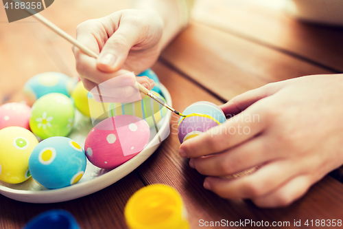 Image of close up of woman hands coloring easter eggs