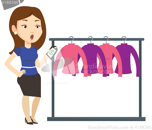 Image of Woman shocked by price tag in clothing store.