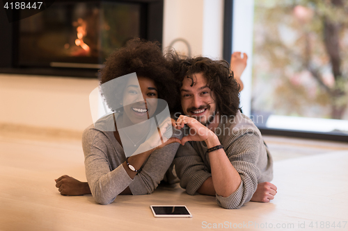 Image of multiethnic couple used tablet computer on the floor