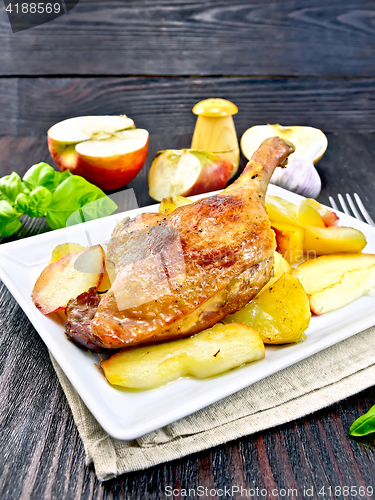 Image of Duck leg with apple and basil in plate on napkin