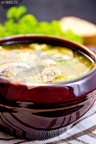 Image of Soup with meatballs and mushrooms in clay bowl on dark board