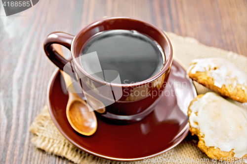 Image of Coffee in brown cup with cookies on dark board