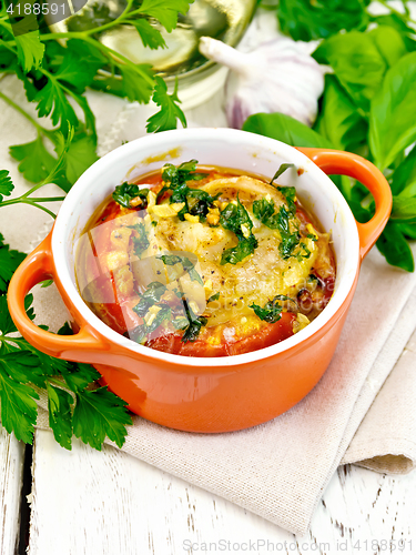 Image of Fish baked with tomato in red pot on napkin