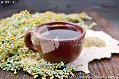 Image of Tea with wormwood in clay cup on board