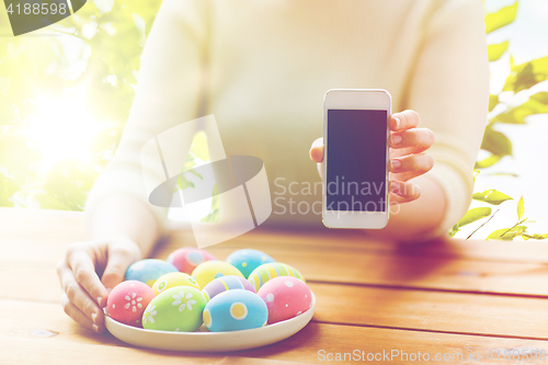 Image of close up of hands with easter eggs and smartphone