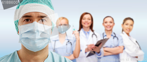 Image of surgeon in mask with group of medics over blue